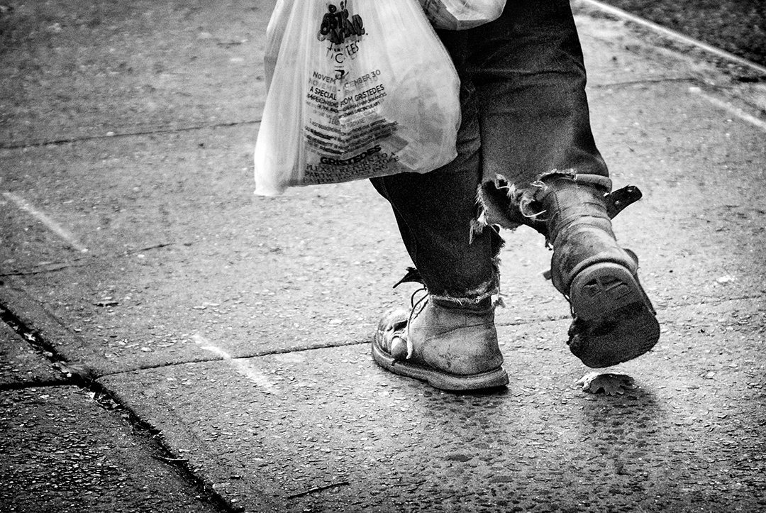 A person carrying a bag, seen at shoe level.